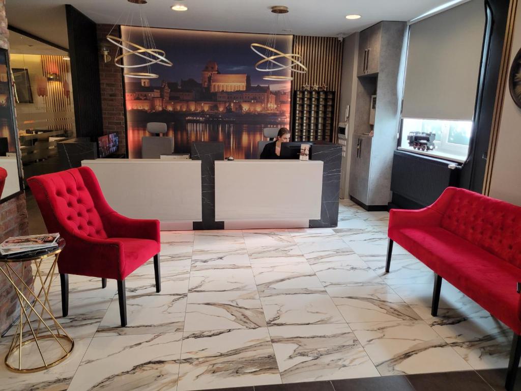 托伦Hotel Przystanek Torun的大堂设有2把红色椅子和前台