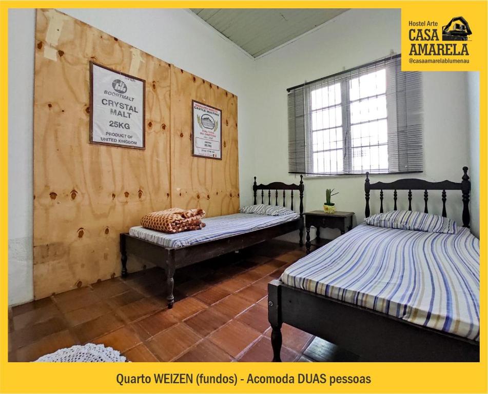 布卢梅瑙Casa Amarela Blumenau Hospedagem Alternativa的一间卧室设有两张床和窗户。
