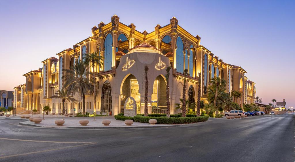 利雅德Madareem Hotel的一座黄色的大建筑,前面有棕榈树