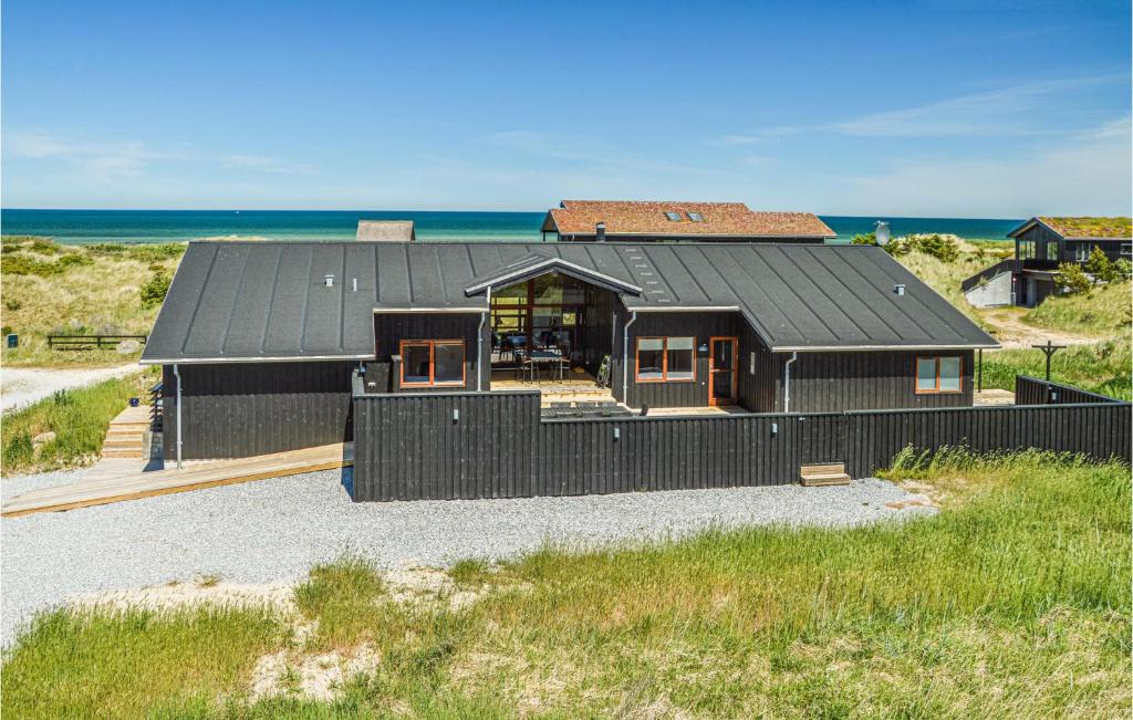 希茨海尔斯Lovely Home In Hirtshals With House Sea View的黑房子,在海滩上设有黑色屋顶