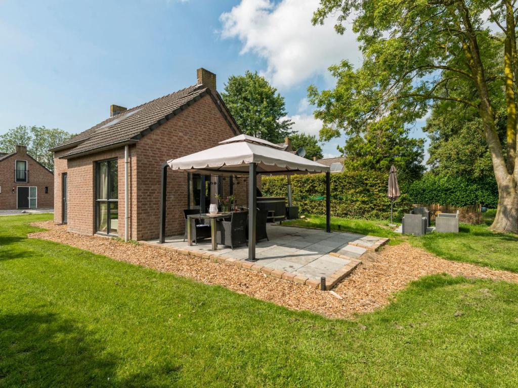 EwijkHoliday Home Forest Cottage Ewijk incl- hot tub by Interhome的一个带桌子和遮阳伞的庭院