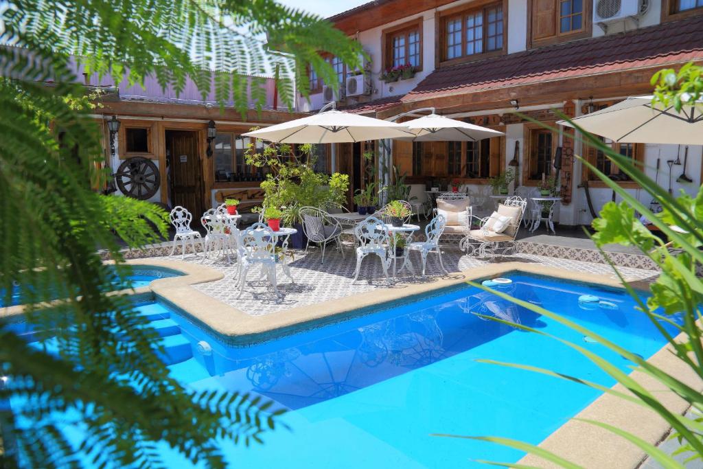 圣克鲁兹Hotel Boutique Vendimia Premium的一个带桌椅和遮阳伞的游泳池