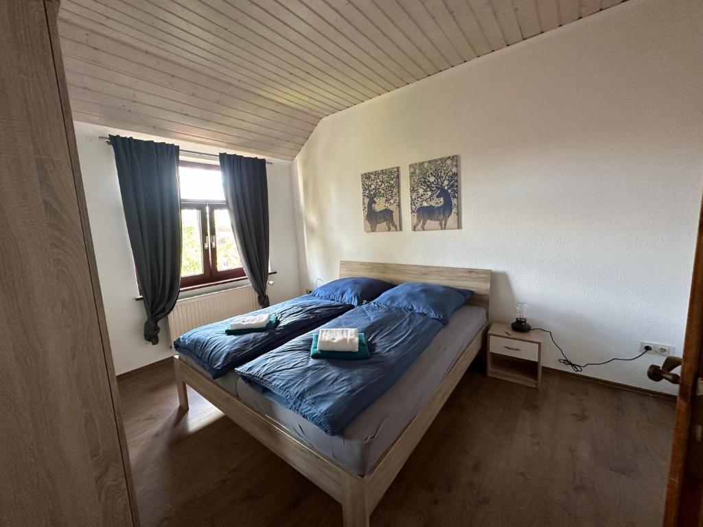 威廉港98qm Wohnung im Villenviertel - Voll ausgestattet mit Balkon und Kamin - WLAN gratis的一间卧室配有一张带蓝色床单的床和一扇窗户。