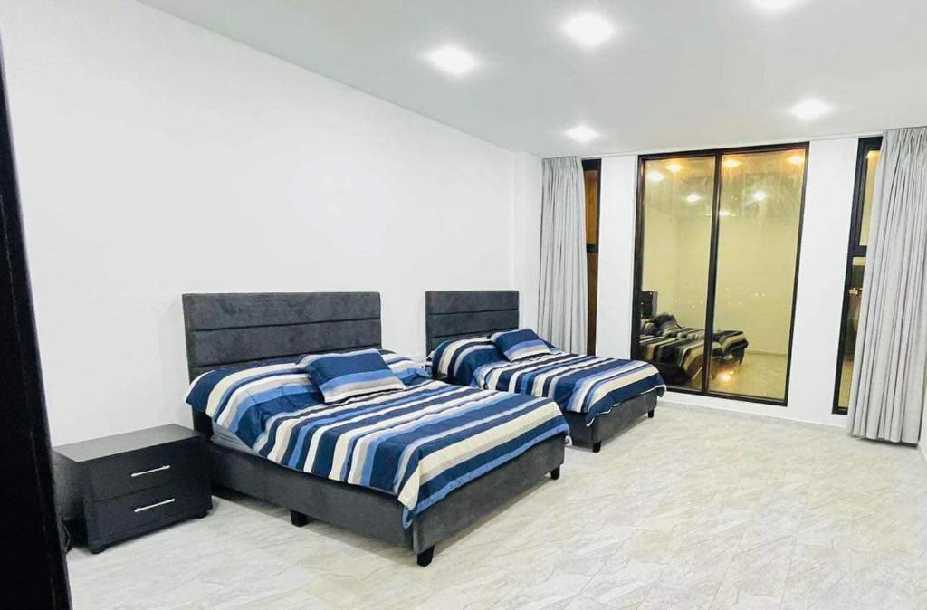Al RamaThe Mansion villa的一间卧室配有两张带蓝白色床单的床