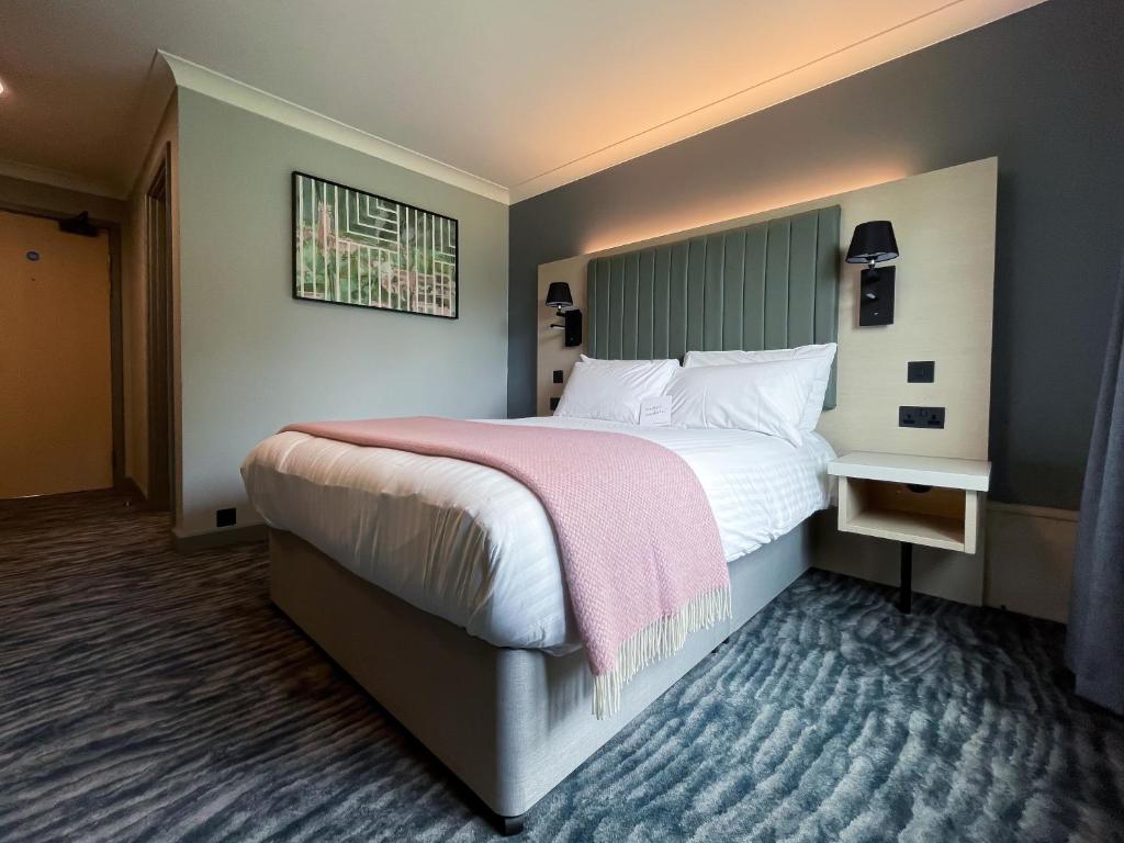 考文垂华威会议中心-斯卡曼酒店的一间卧室配有一张带粉色毯子的大床