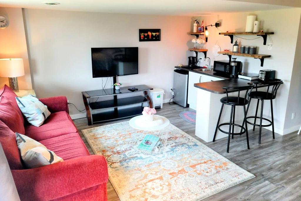 温尼伯Cozy Private Suite的一间带红色沙发的客厅和一间厨房
