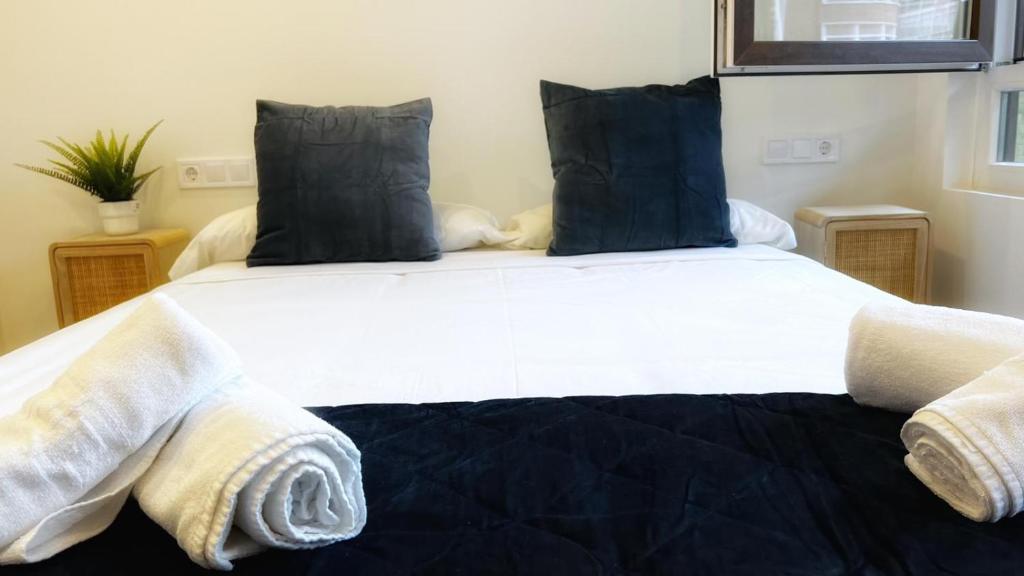 毕尔巴鄂Deustown Apartamentos的卧室配有带蓝色枕头的大型白色床