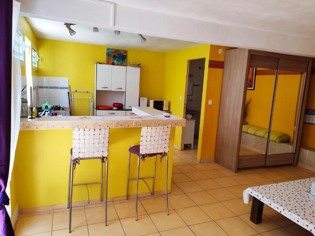 旧阿比唐Gîtes TAINACO的厨房设有黄色的墙壁、柜台和凳子