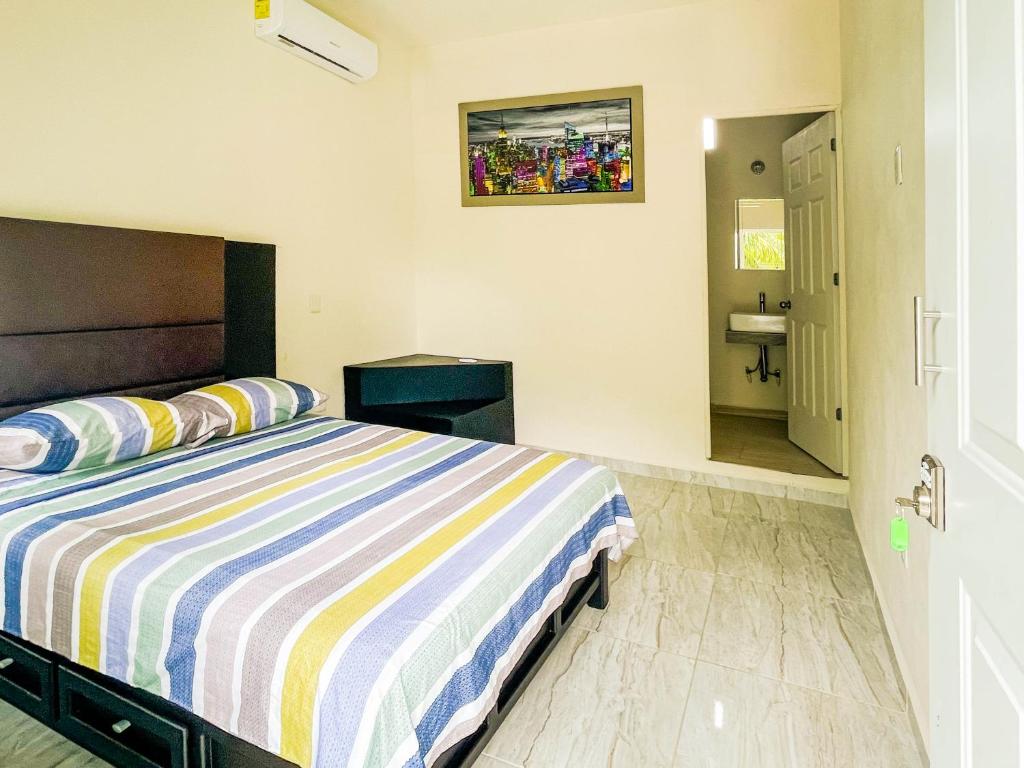 巴卡拉尔Hotel Vias Maya Bacalar的一间带条纹床的卧室和一间浴室
