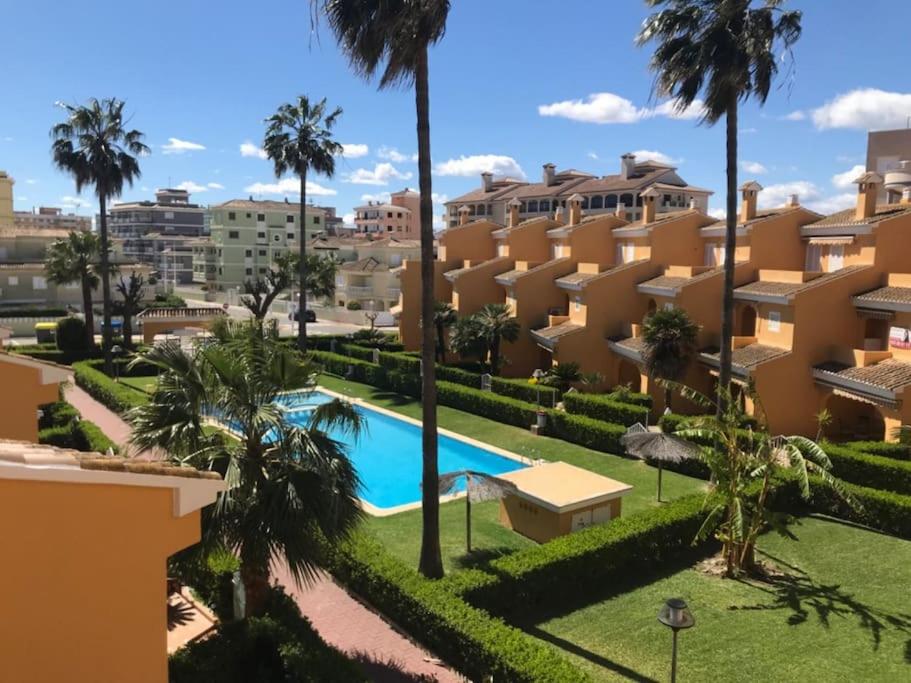 苏埃卡Casa adosada junto a la playa de El Perelló的享有带游泳池和棕榈树的度假村的正面景色
