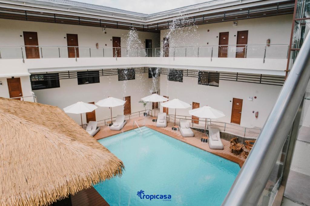科隆Tropicasa Coron Resort & Hotel的一个带椅子和遮阳伞的室内游泳池