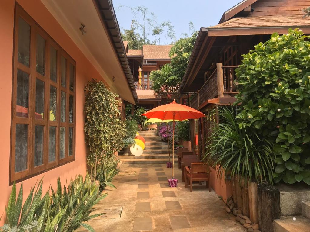 Ban Pa Sangบ้านยุ้งฮีลล์รีสอร์ท Baan Yung Hill Resort的庭院配有遮阳伞和桌椅。
