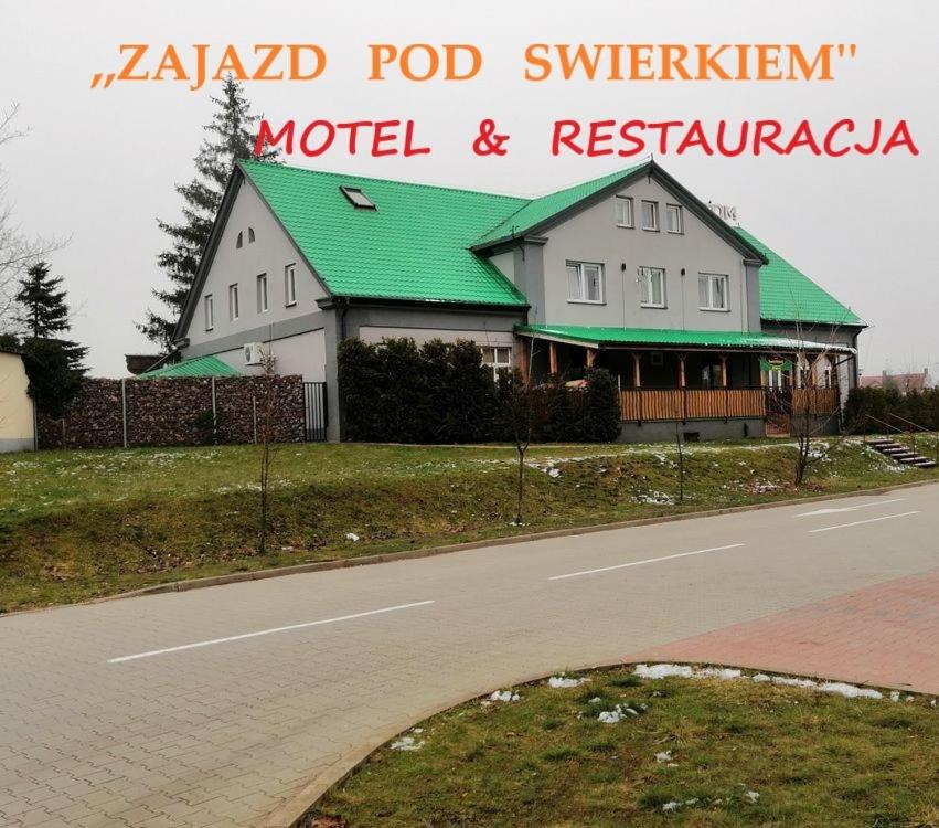 格拉耶沃Zajazd Pod Świerkiem的一条路上的白色大房子,有绿色屋顶