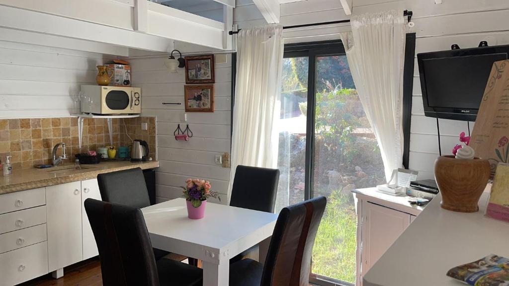 梅图拉בקתות עץ סקנדינביות במטולה的厨房配有白色的桌椅和窗户。