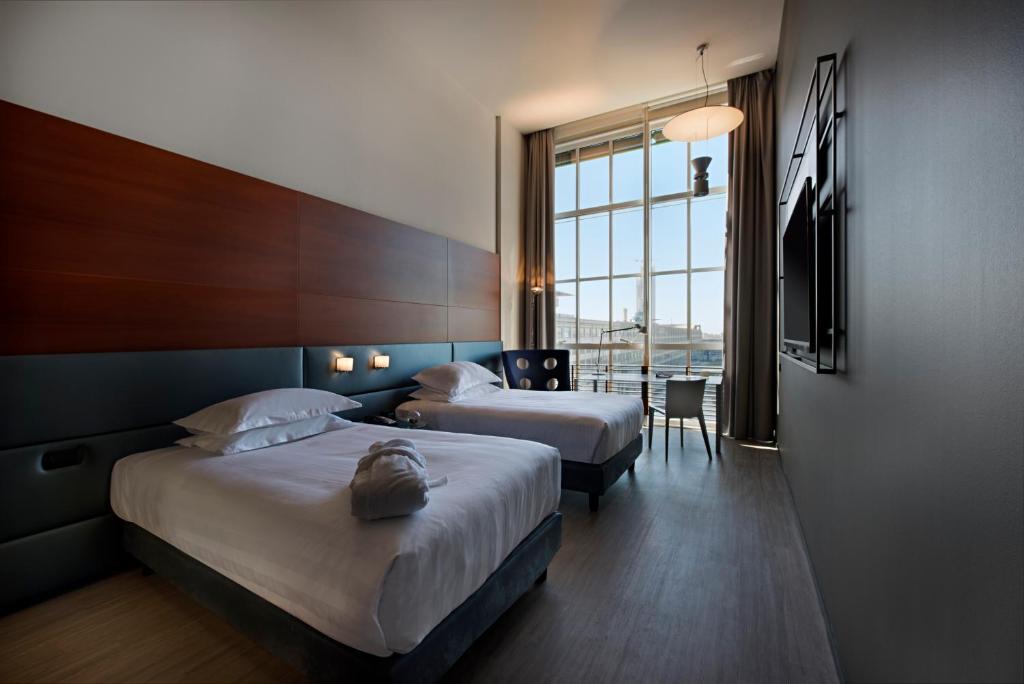 都灵都灵灵格托希尔顿逸林酒店的酒店客房设有两张床和窗户。