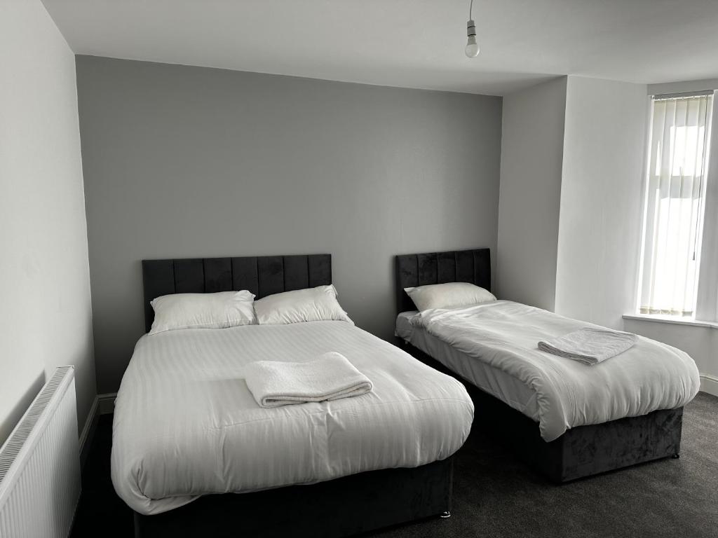 曼彻斯特OYO Cheetham Hill Guest House的白色墙壁客房的两张床
