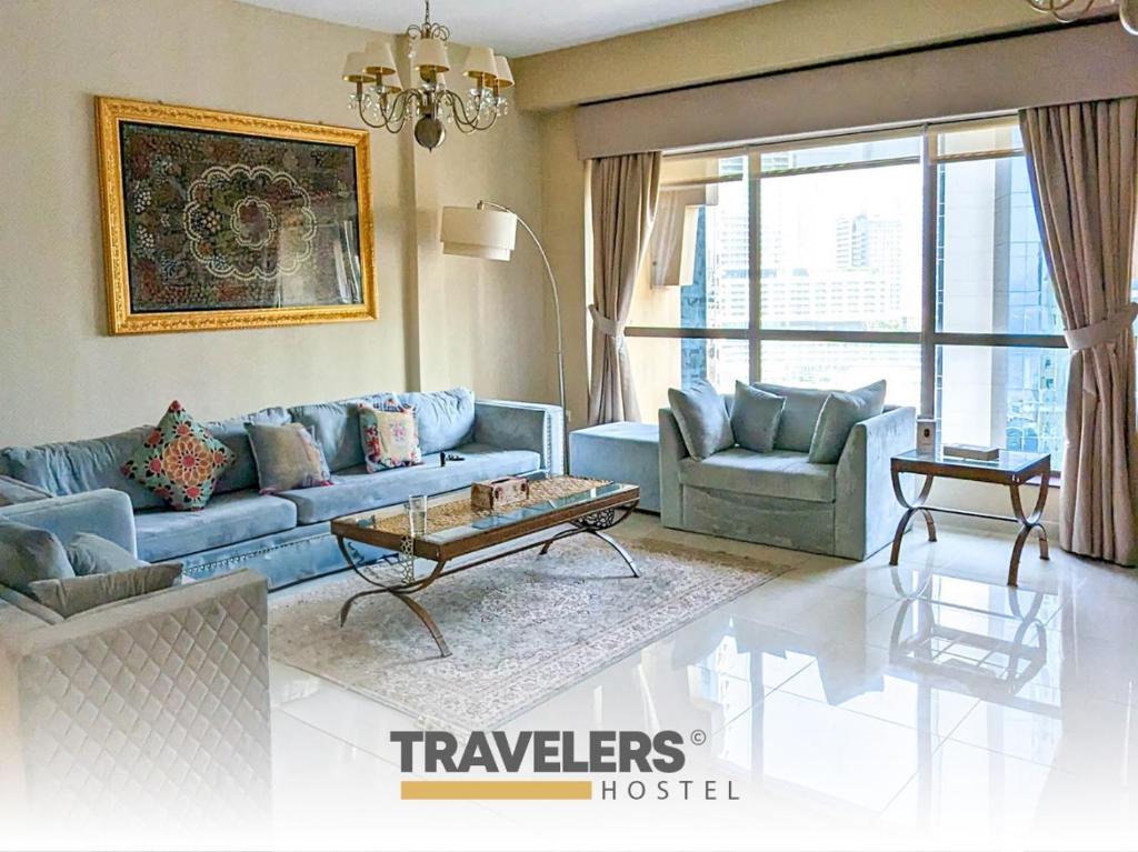 迪拜Travelers - Dubai Marina Hostel的客厅配有蓝色的沙发和两把椅子