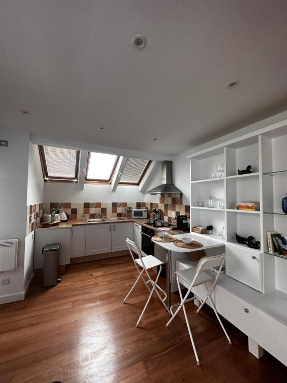 伦敦Studio flat in the heart of Hampstead, London的厨房配有白色橱柜和桌椅