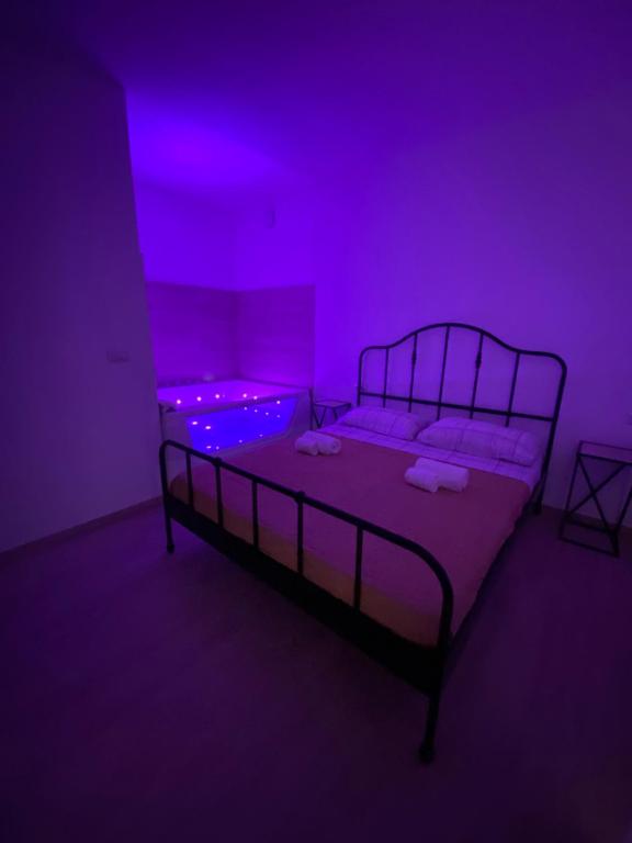 阿尔盖罗Maris Suite - Appartamento con vasca idromassaggio的一间暗室,配有一张紫色灯床