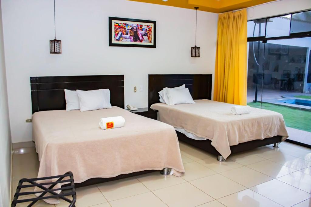 瓦努科La Estancia Hotel的带窗户的客房内的两张床