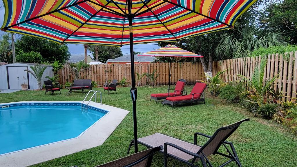 西棕榈滩West Palm Beach Tropical Oasis的游泳池旁的彩色遮阳伞和椅子
