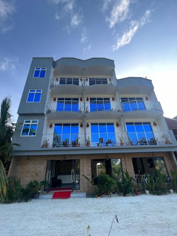 图杜Rihiveli Residence Thoddoo的海滩上一座带蓝色窗户的大型建筑