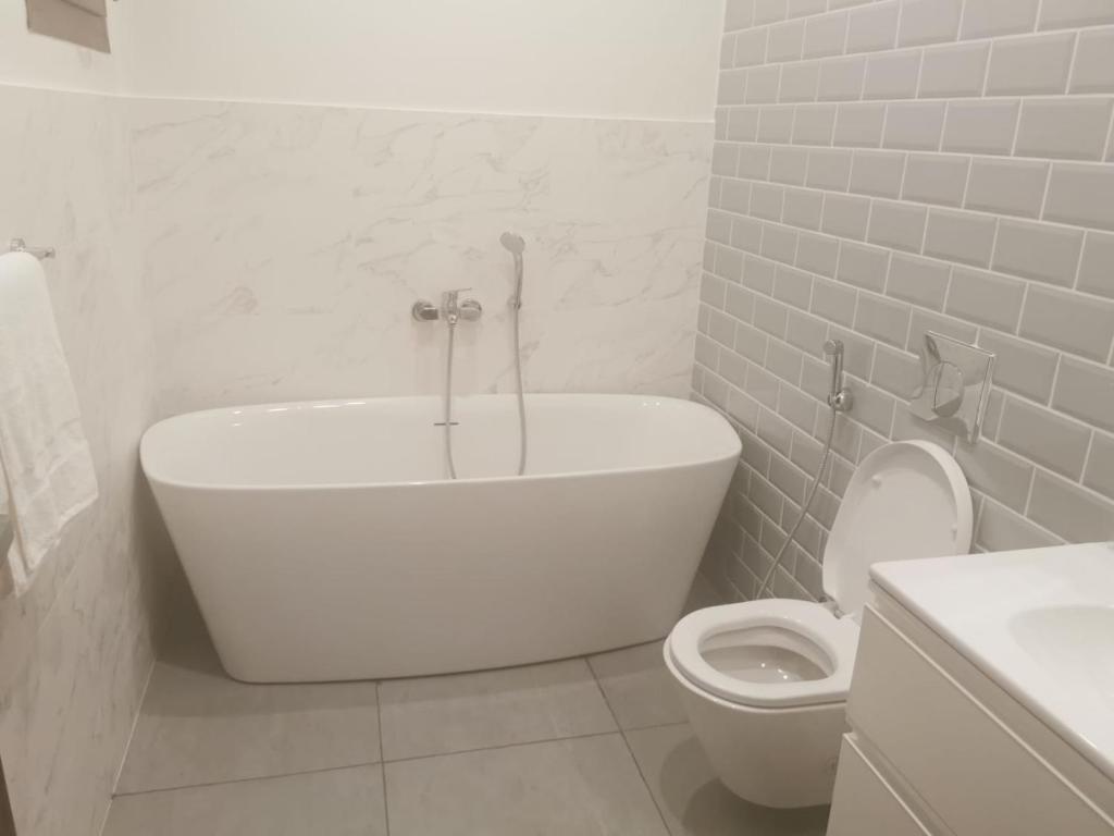 Wādī KhasbarHawana VIP Private Apartment的白色的浴室设有浴缸和卫生间。