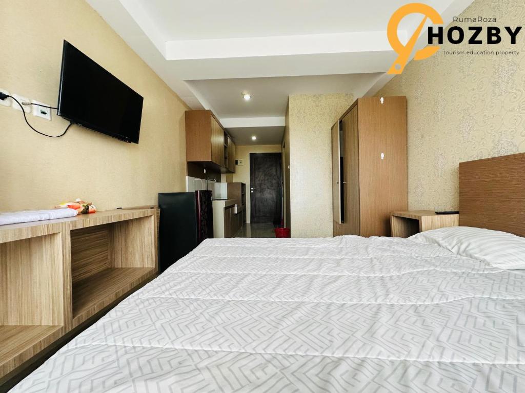 SunggalSkyview Premier Suites Hozby的卧室配有一张大床,墙上配有电视