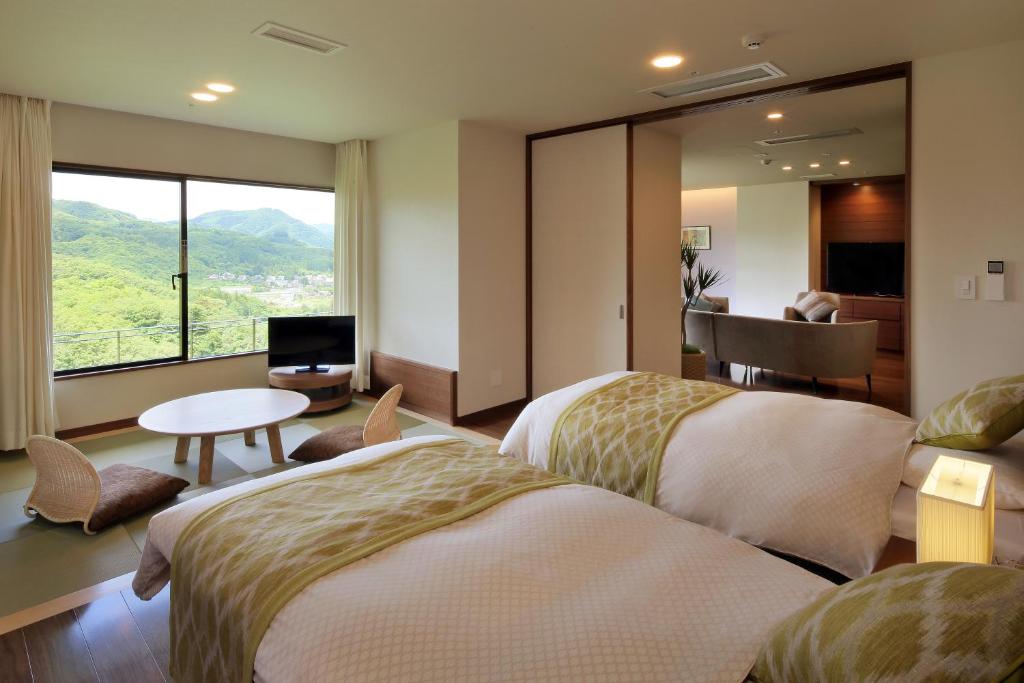 仙台仙台秋保温泉 篝火の湯 緑水亭的酒店客房设有两张床和一张桌子。