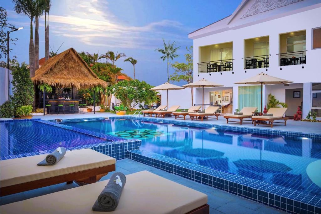 暹粒Sala Siem Reap Hotel的度假村的游泳池,配有椅子和遮阳伞
