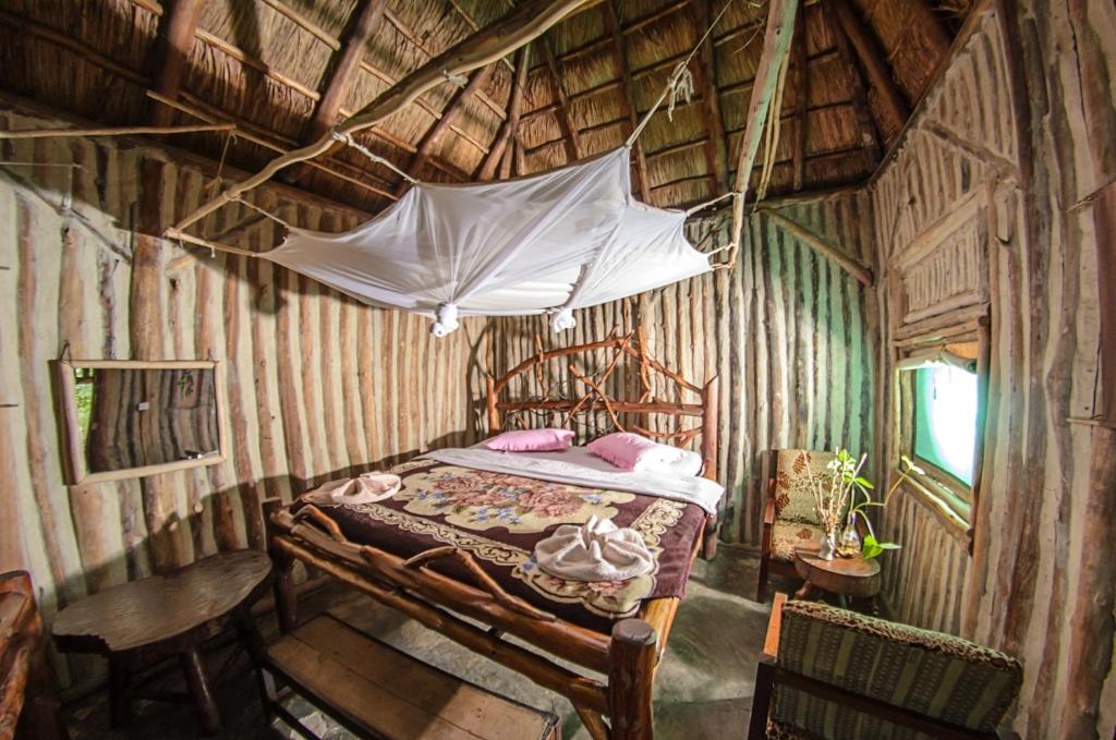 RubiriziDave the Cave Eco Lodge and Cultural Campsite的木制客房内的一间卧室配有一张天蓬床