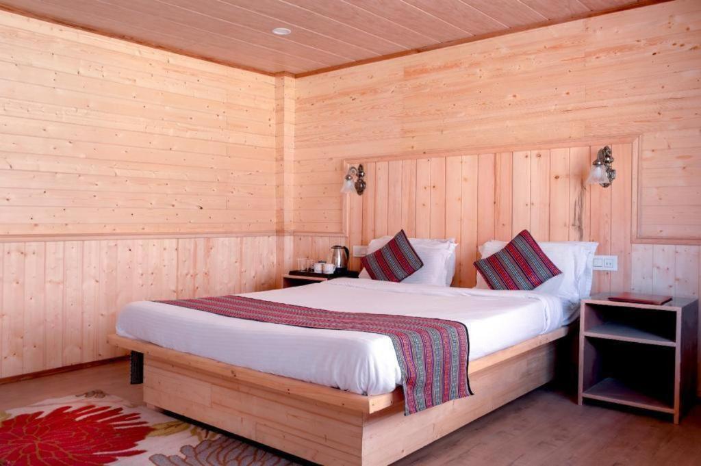 拉冲Keerong Cottages Lachung的木制客房内的一间卧室,配有一张床