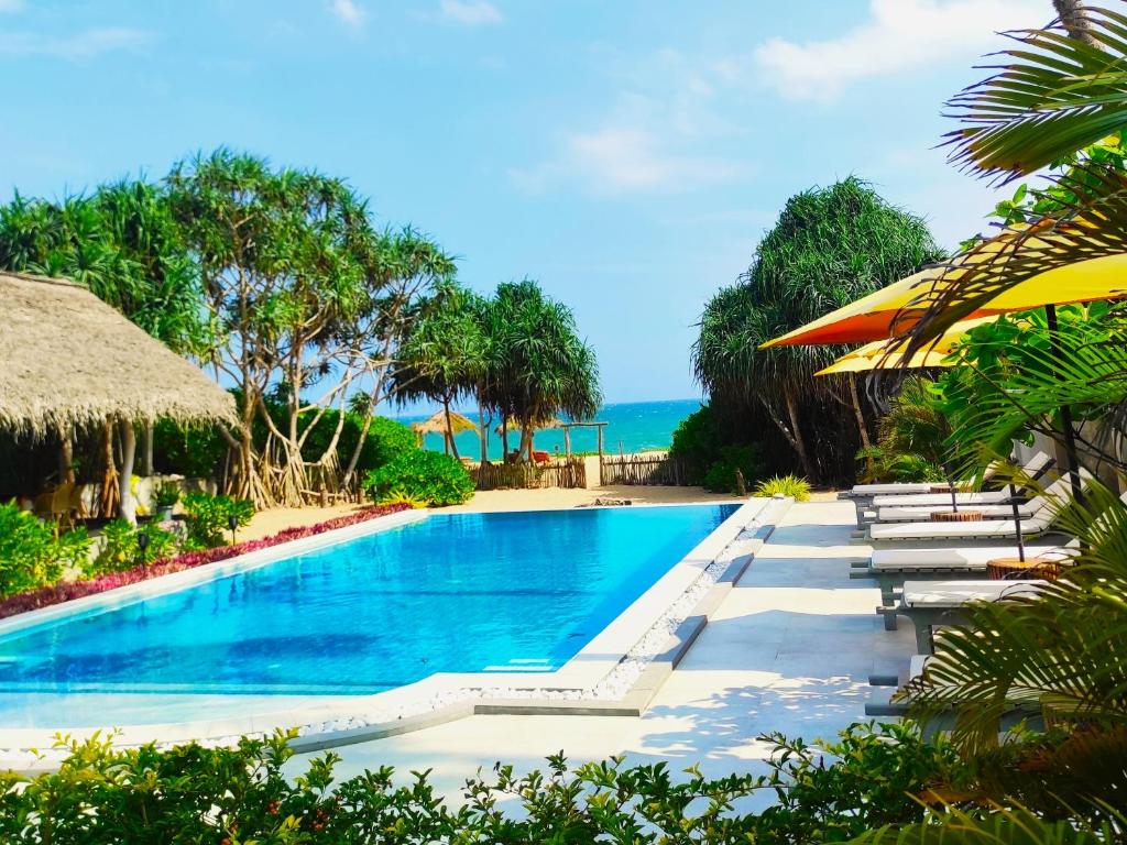坦加拉Sleeping Elephant Beach Resort的度假村的游泳池,配有椅子和遮阳伞
