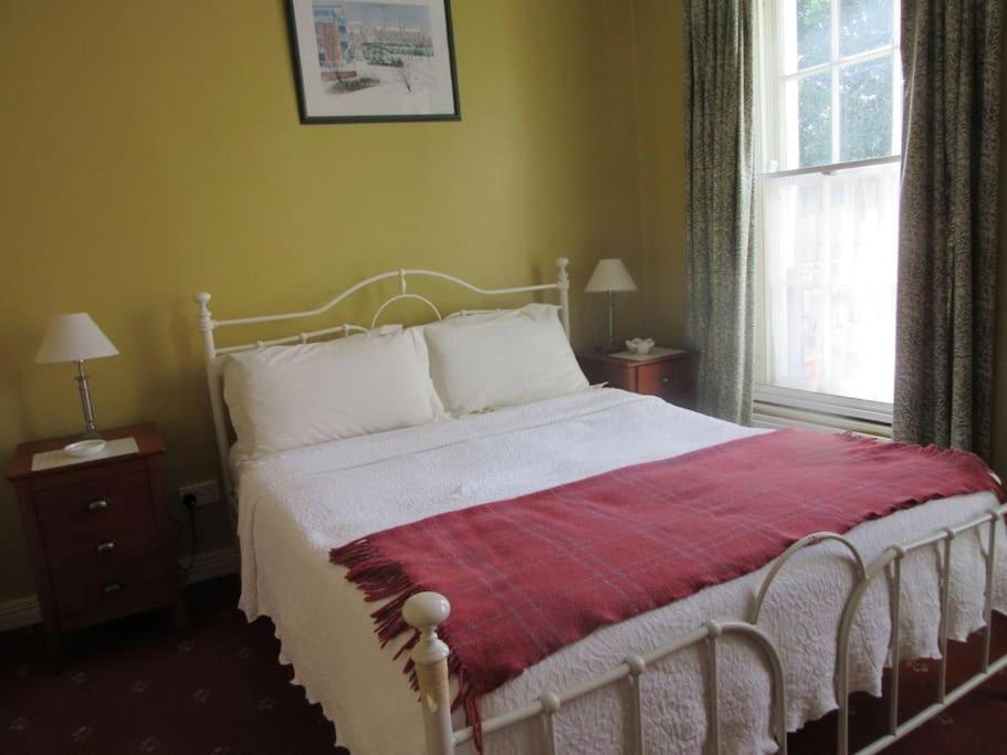 伦敦德里Cathedral Cottage的卧室配有一张带红色毯子的白色床