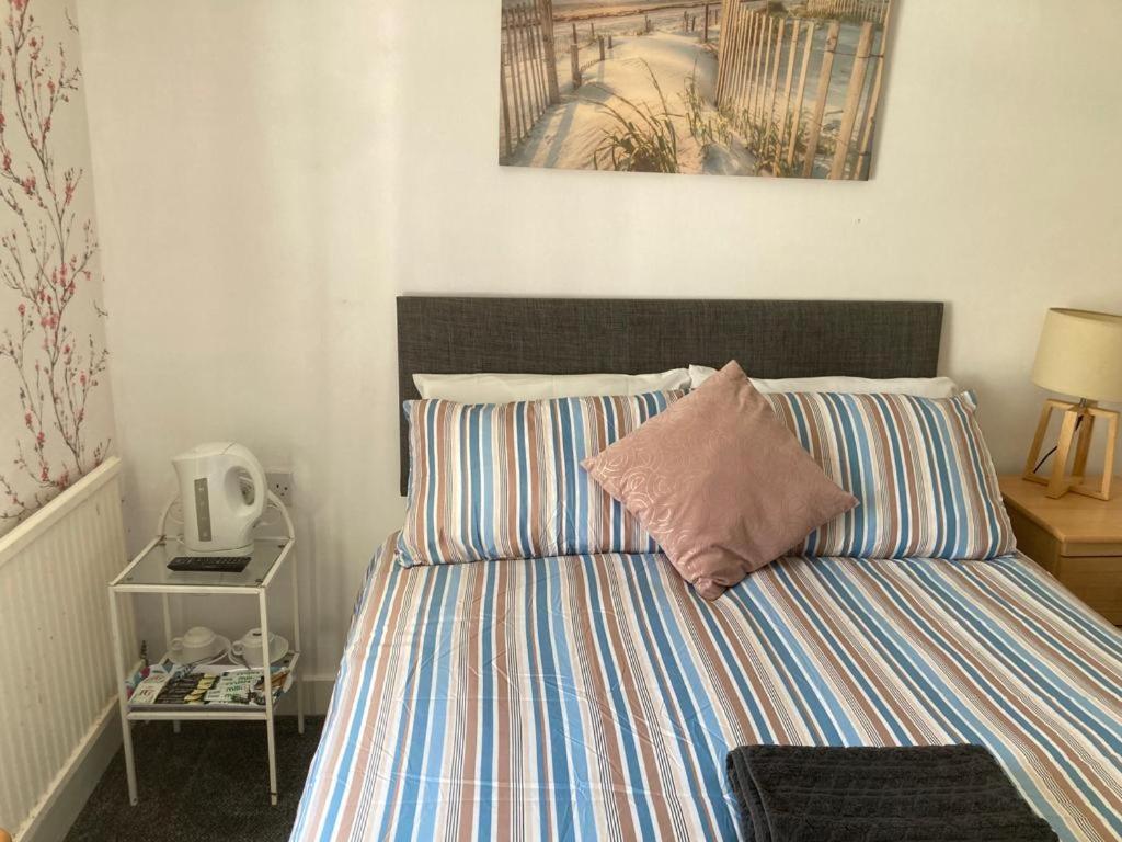 LlangristiolusHolland arms hotel的卧室内的一张带条纹棉被的床