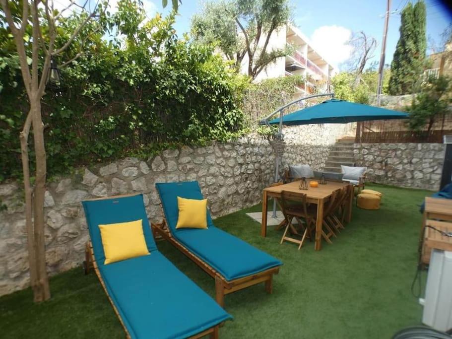 锡富尔勒普拉日Studio avec jardin proche plage Six Fours/Sanary的天井配有两把椅子和一张桌子及遮阳伞
