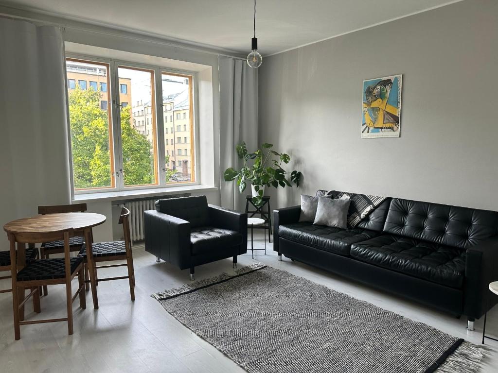 赫尔辛基Eteläinen Hesperiankatu的客厅配有黑色真皮沙发和桌子