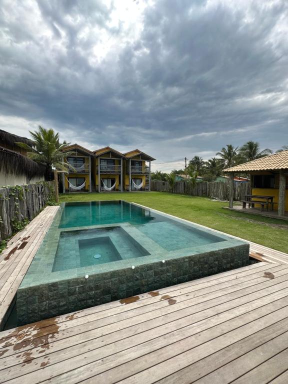 卡拉伊瓦Tamikuã Mar Pousada的一个带木甲板和房子的游泳池
