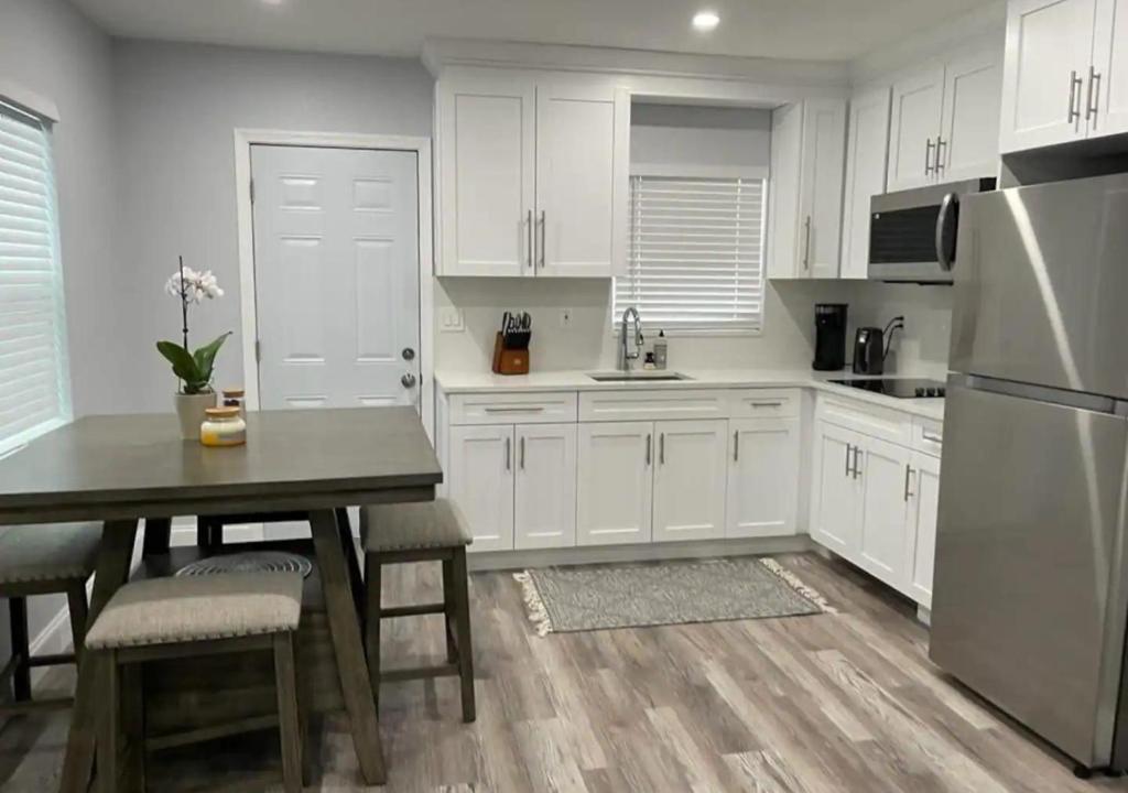 西棕榈滩Downtown West Palm Apartment Near Airport的厨房配有白色橱柜、桌子和冰箱。