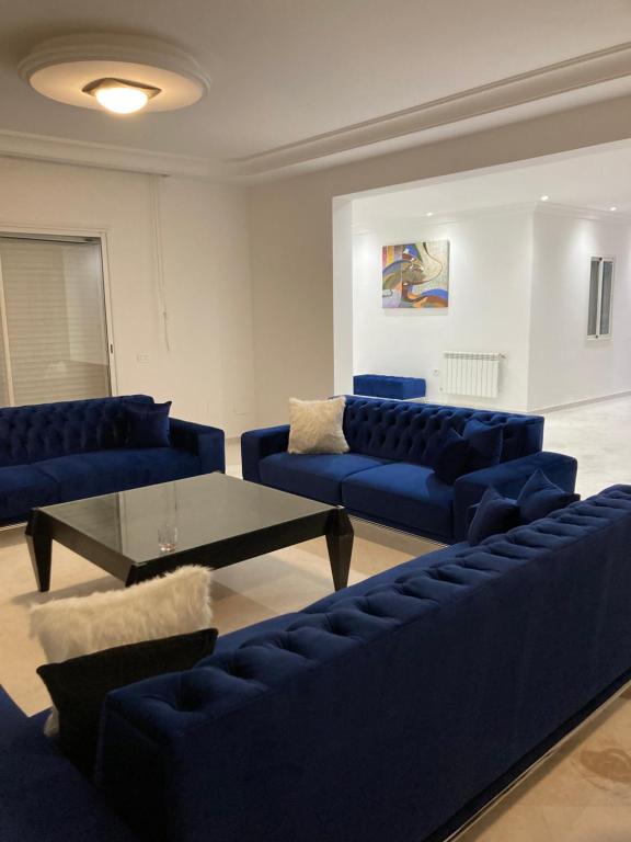 突尼斯Appartement haut standing 170 m2的客厅配有蓝色的沙发和桌子
