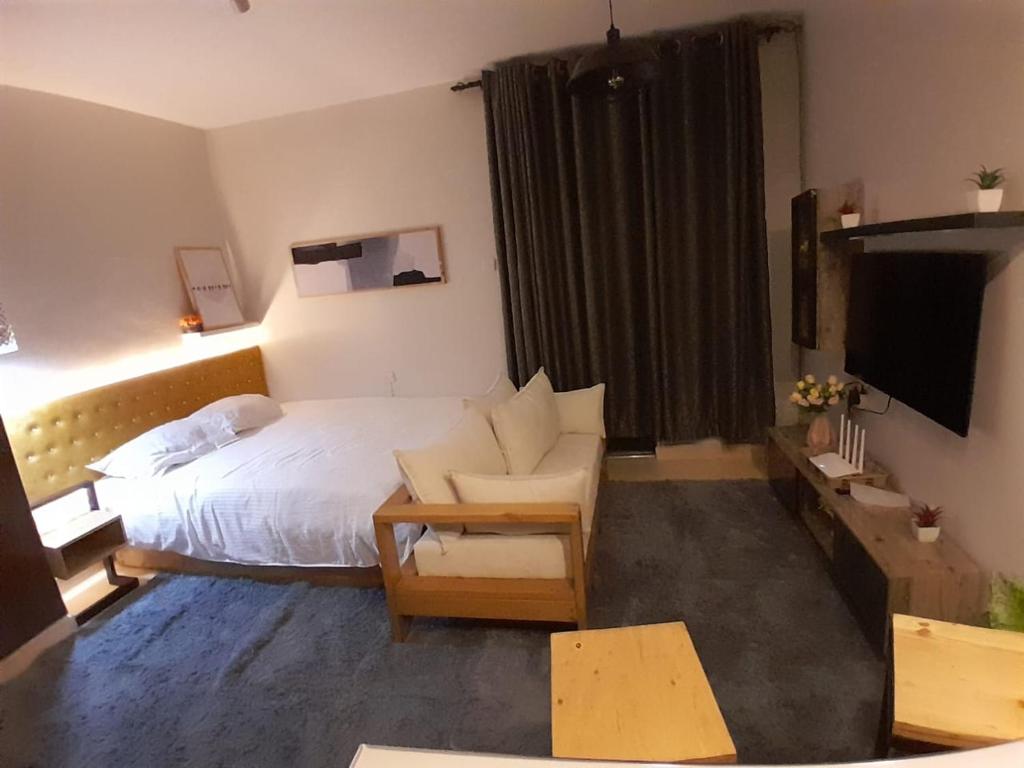 BungomaEnN Lovely En suite studio apartment的酒店客房配有床、沙发和电视。