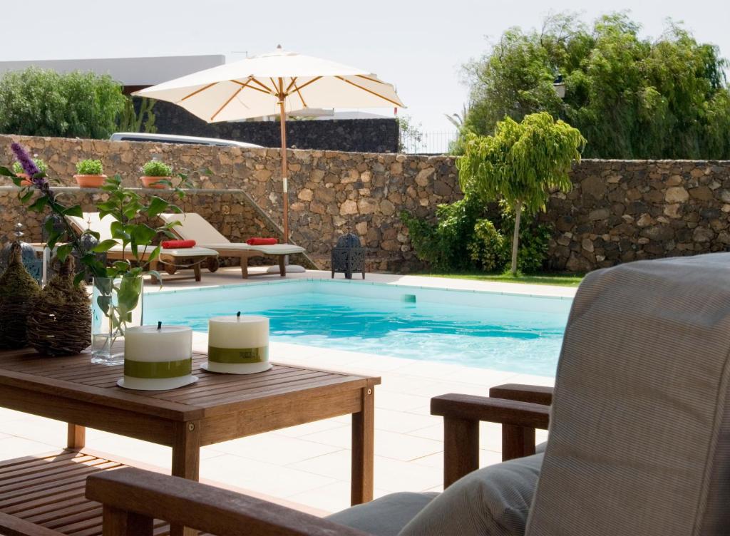 卡门港Villa Coral的一个带桌椅和遮阳伞的游泳池