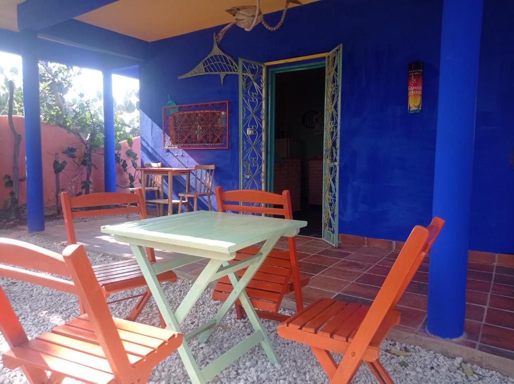 阿拉卡蒂MERMAID HOUSE, casa charmoso, wifi, parking, jardim, cozinha, central CANOA QUEBRADA的蓝色墙壁的房间里一张桌子和椅子