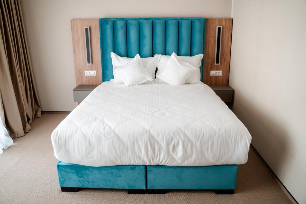 DrăgăşaniRiver Park Hotel的一张大床,在房间内有一个蓝色床头板