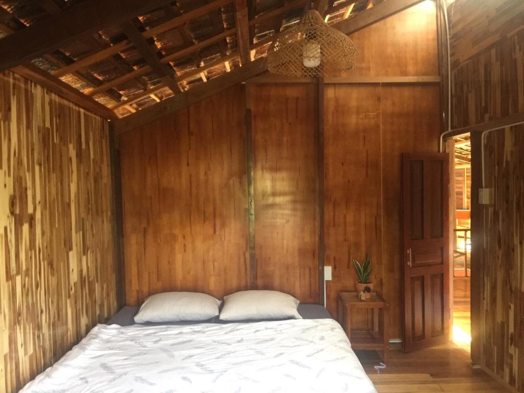 大叻Elon Coffee Farmstay的卧室配有木墙内的一张床