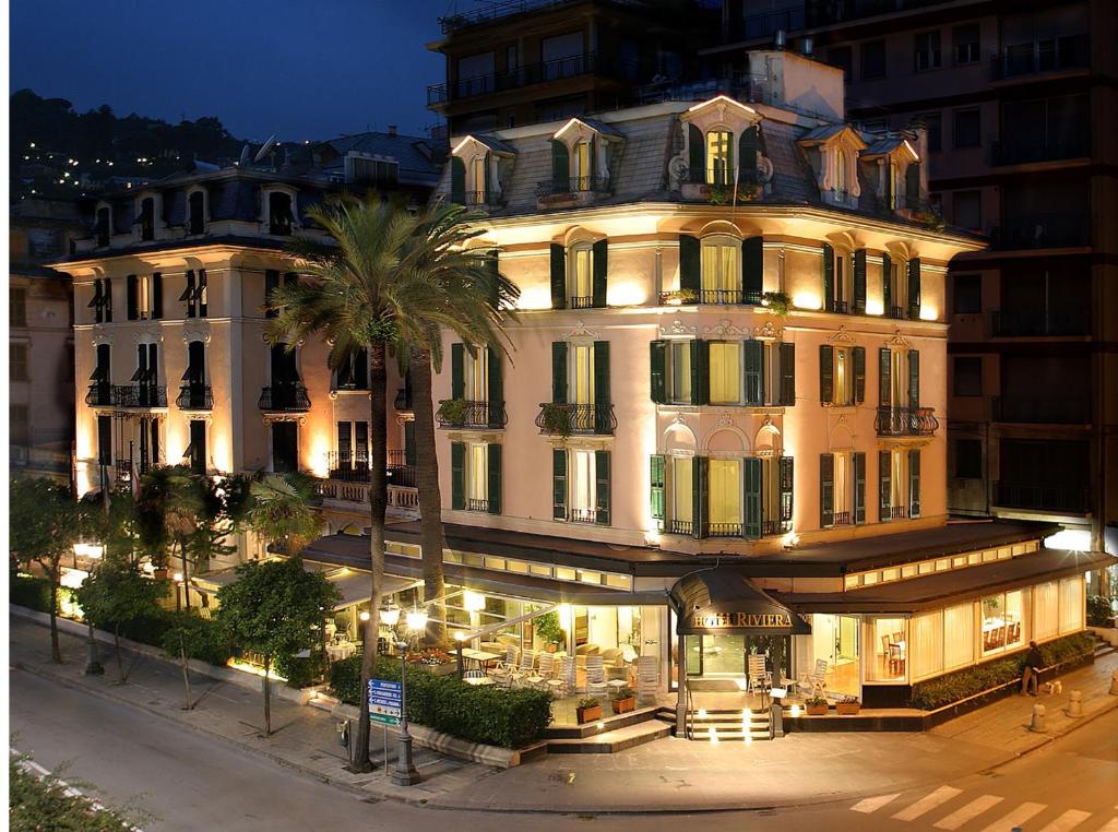 拉帕洛里维埃拉酒店的一座白色的大建筑,前面有一棵棕榈树
