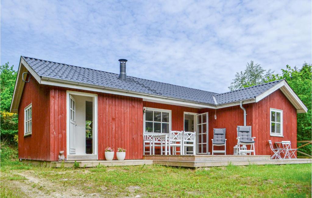 埃贝尔托夫特Cozy Home In Ebeltoft With Wifi的红色的房子,上面有甲板和椅子