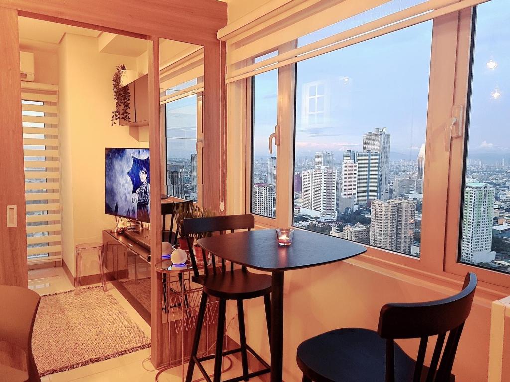 马尼拉Cozy Penthouse Suite w Balcony - Amazing Manila Bay View and City Skyline near MOA的客房设有桌椅和大窗户。