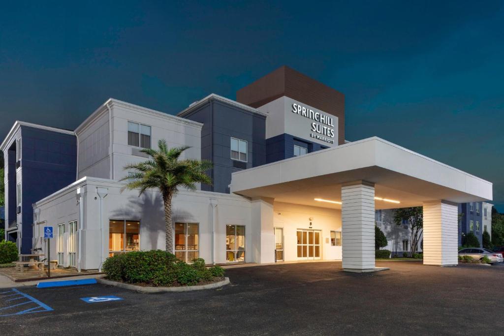 巴吞鲁日巴吞鲁日南万豪春季山丘套房酒店的一座白色的大建筑,前面有一棵棕榈树