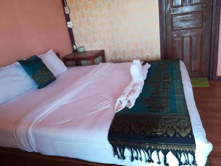 Muang KhôngChampa Guesthouse的一间卧室配有一张带粉色床单的大床和一扇门